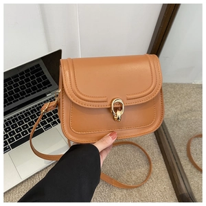 Détail du sac bandoulière en cuir camel avec rabat en U et boucle dorée à double anneau