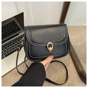 Détail du petit sac noir en similicuir brillant avec boucle dorée à double anneau