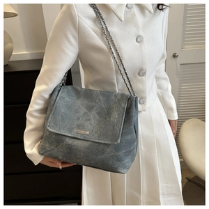 Détail du sac bandoulière gris avec tissu délavé et plaque de logo argentée élégante