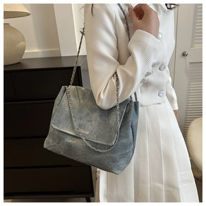 Détail de la texture en cuir mat avec bandoulière chaîne et fermeture à rabat