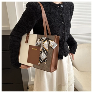 Detail of color-block tote bag featuring silk scarf handle and FASHION logo