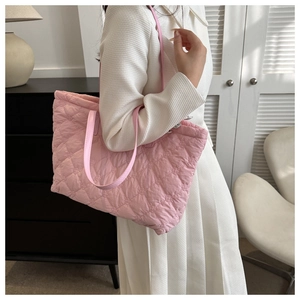 Detailed view of pink quilted tote bag showing rhombus stitching texture and long shoulder strap