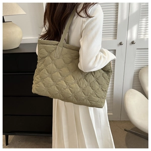Olive green quilted tote bag with diamond stitching shown on shoulder for daily use