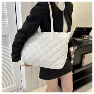 Detail of white quilted tote bag featuring padded diamond stitching and soft nylon texture