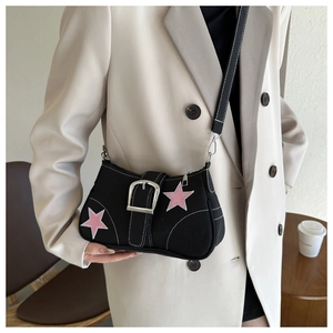 Detail of black canvas shoulder bag featuring pink star patches and a large silver buckle