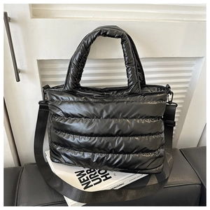 Détail du sac fourre-tout matelassé noir avec bandoulière tissée sur des livres blancs