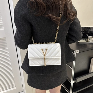 Sac bandoulière carré blanc matelassé avec logo V doré et pompon porté par un mannequin