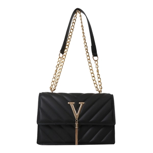 Sac bandoulière matelassé noir avec logo V doré et pompon sur un fond blanc neutre