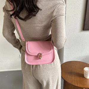 Sac bandoulière rose pour femme avec boucle dorée dans un décor intérieur minimaliste