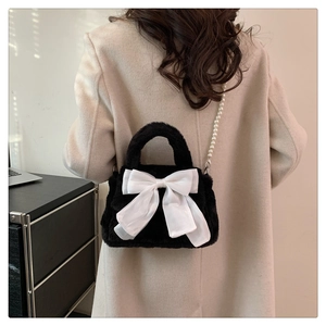 Détail d'un sac à main en peluche noire avec nœud blanc et bandoulière en perles