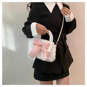 Détail du sac à main en peluche blanche avec grand nœud en satin rose et bandoulière en perles
