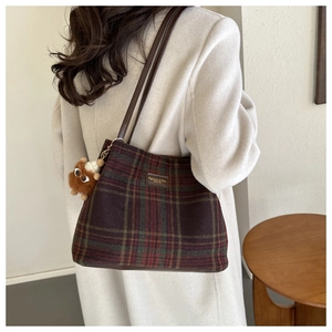 Detalle de bolso tote de lana a cuadros con correa de cuero y colgante de peluche suave