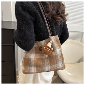 Detalle del bolso tote de cuadros marrones con etiqueta de cuero y colgante de peluche