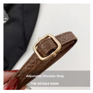 Macro shot of dark brown crocodile pattern adjustable strap with gold metal buckle