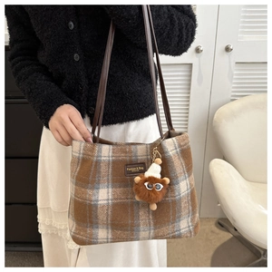 Detalle de bolso tote retro a cuadros con parche de cuero y amuleto de peluche