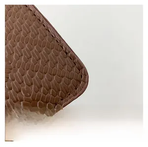 Macro view of brown faux snake texture and stitching details on the fashion handbag