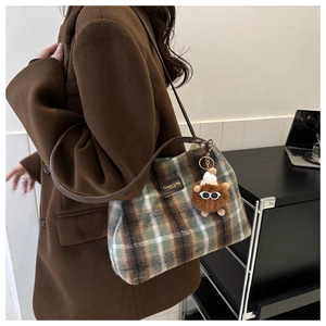 Detalle de bolso de hombro a cuadros en tela de felpa con un lindo pompón marrón decorativo