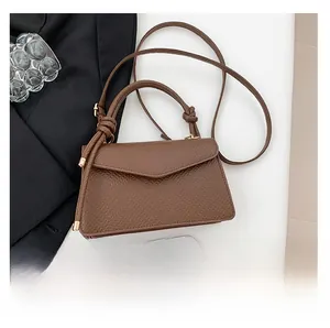 Detailed macro view of the brown lychee-patterned leather surface and knotted handle