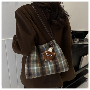 Detalle del bolso de hombro a cuadros de felpa con un amuleto de monstruo