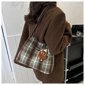 Detalle del bolso tote de felpa a cuadros con logo de cuero y colgante de monstruo suave