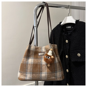 Detalle del bolso tote retro de tweed a cuadros con un lindo colgante de monstruo de peluche