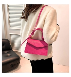 Model wearing a rose pink crocodile-embossed envelope crossbody bag with top handle