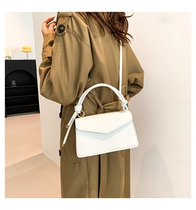 Detail of white textured mini square bag with knotted handle and lizard skin pattern