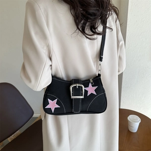 Minimalist black canvas shoulder bag with pink stars and silver buckle on white coat