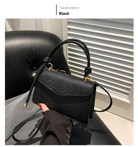 Detail of black textured crossbody bag with gold hardware and top handle design