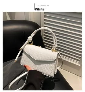 Detail of white lizard-patterned handbag with round woven handle and gold hardware on black chair