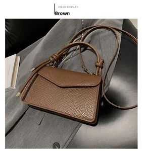 Detail view of the brown leather shoulder bag with knot handle and triangle flap closure