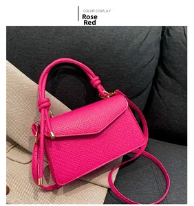 Detail of rose red crossbody bag with knot handle and litchi grain leather texture