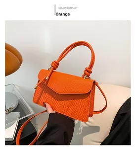 Detail of orange handbag with snake pattern texture and twisted rope knot handle design