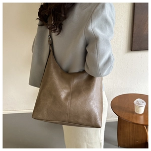 Detail of dark brown leather tote bag with vintage texture and adjustable strap on model