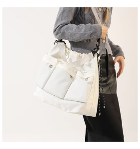 Detail of white nylon tote bag featuring three front pockets and wide shoulder strap