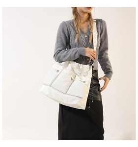 Detail of white canvas shoulder bag featuring three front flap pockets and drawstring closure