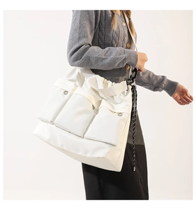 Detail of white multi-pocket tote bag with silver buckles and tactical woven strap details