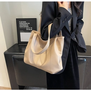 Detail showing high-capacity beige PU leather tote bag worn as a shoulder bag