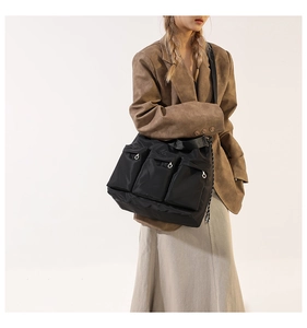 Detail of black nylon shoulder bag featuring multiple functional front zipper pockets