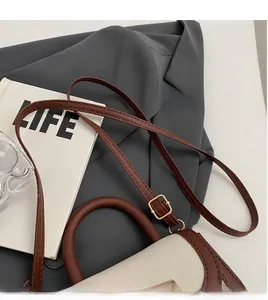 Détail du sac selle en cuir contrasté avec boucle en métal doré et bandoulière réglable