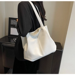 Macro detail of creamy white tote bag with fine leather texture and vertical stitch line