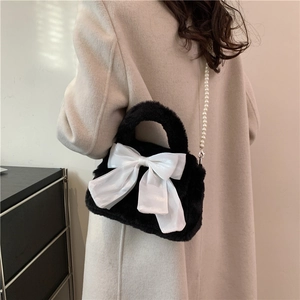 Stylish black plush crossbody bag featuring a large white satin bow and pearl shoulder strap