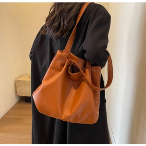 Detailed side view of the caramel leather tote bag showing fine stitching and soft texture