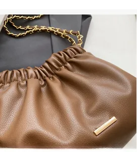 Close-up of brown pleated bucket bag with lychee grain texture and gold chain strap