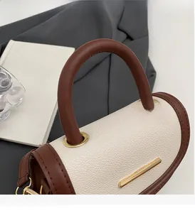 Détail du sac à main en cuir blanc avec poignées marron et fermoir en métal doré
