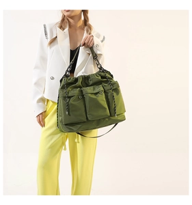 Detail of army green nylon shoulder bag with triple front pockets and drawstring closure