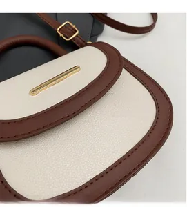 Détail du sac selle en cuir grainé crème avec surpiqûres marron et fermoir doré