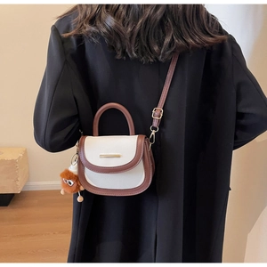 Détail du sac selle blanc en cuir grainé avec bandoulière marron et breloque peluche