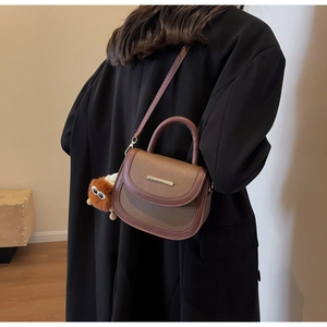 Vue détaillée d'un sac besace marron vintage avec texture litchi et un charm monstre en peluche
