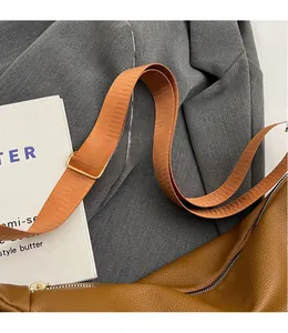 Detail of adjustable nylon shoulder strap with gold buckle on brown lychee texture bag